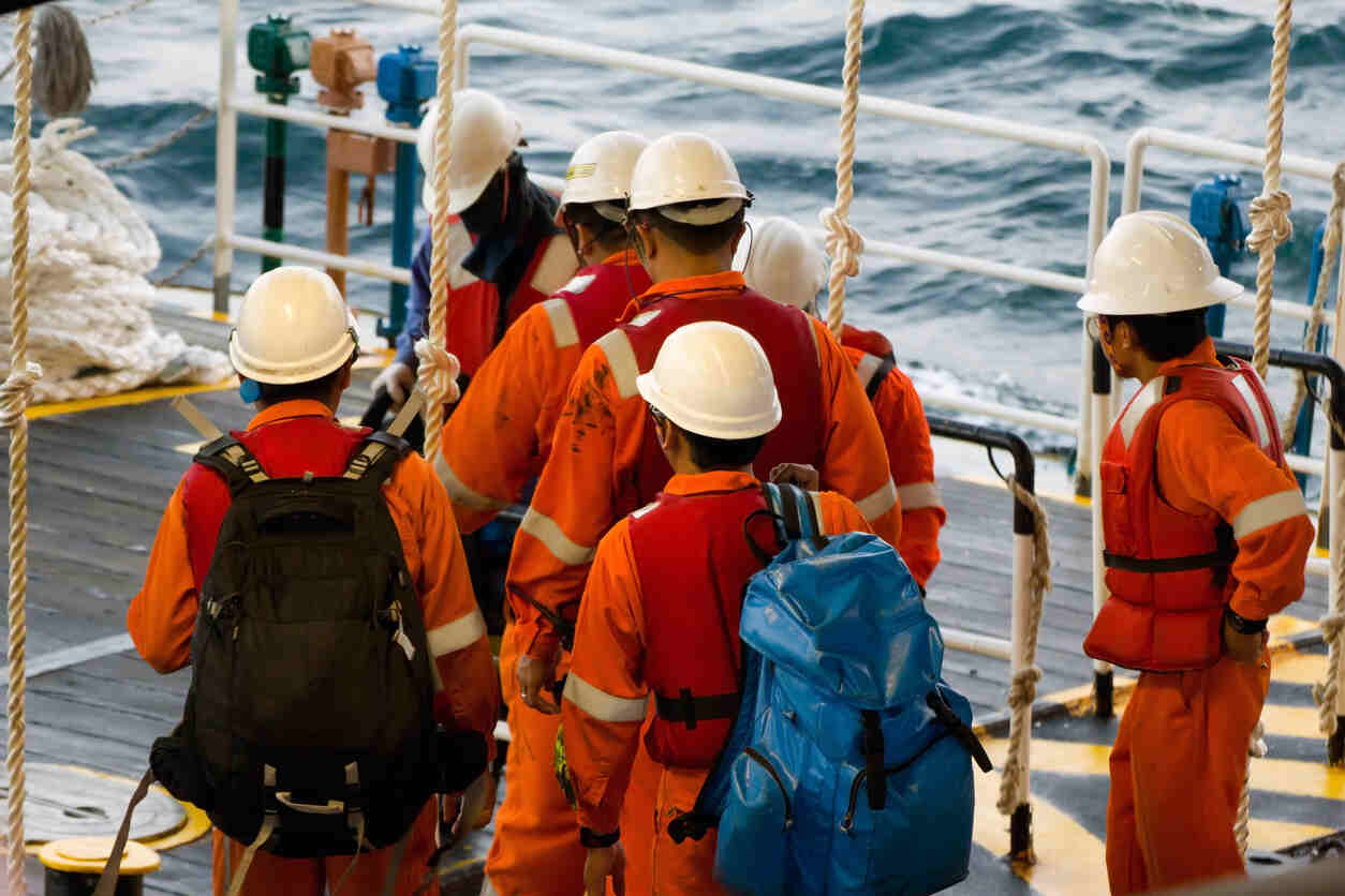 Crew members in safety gear walking on a vessel, representing the distinct nature of maritime and land-based worker injuries.